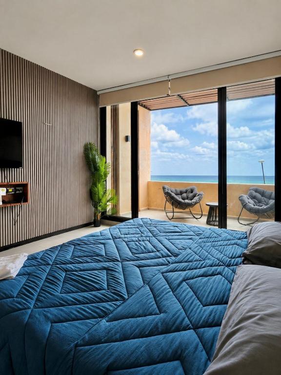 a bedroom with a blue bed with a view of the ocean at Villa oasis among the palms in Telchac Puerto