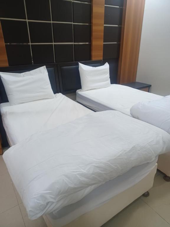 two beds in a room with white sheets and pillows at مؤسسة علي عايض سداح الدوسري للمقاولات in Abu Arish