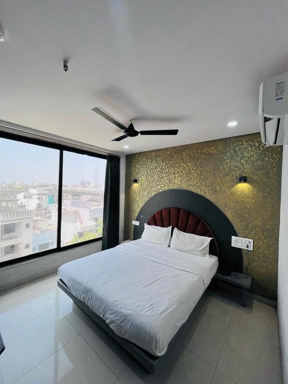 a bedroom with a large bed with a large window at Hotel 7 Square in Surat