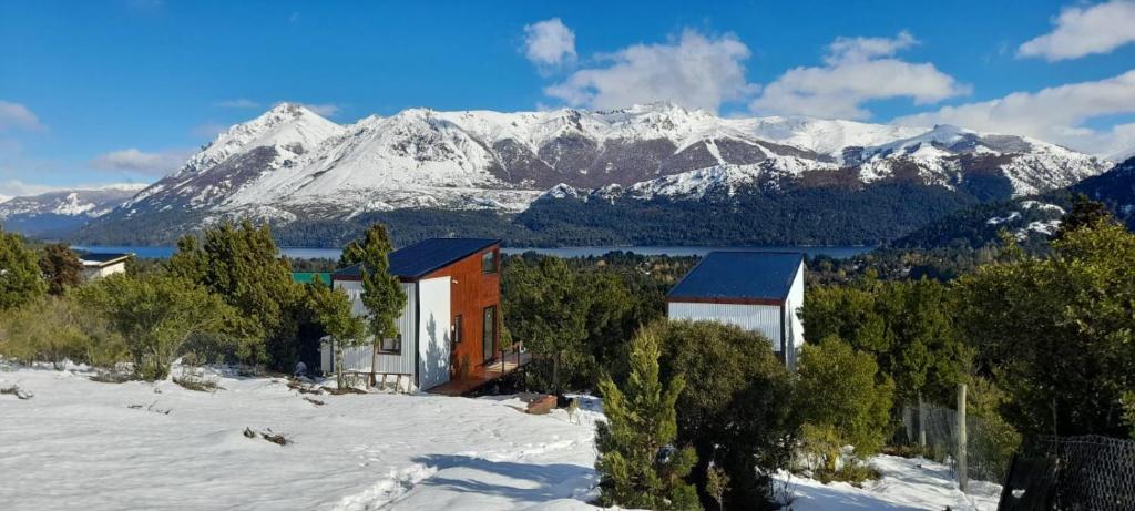 a house in the snow with mountains in the background at De las Melosas Tiny House in San Carlos de Bariloche
