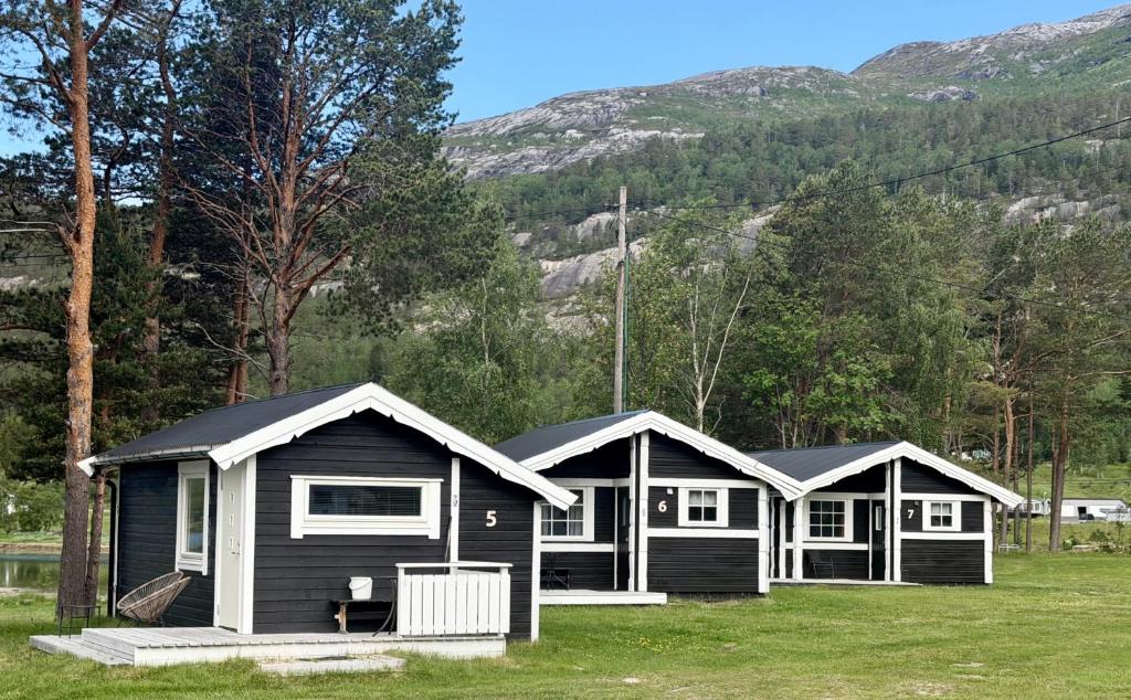 two black and white cottages with mountains in the background at Mørsvikbotn Camping AS in Mørsvik