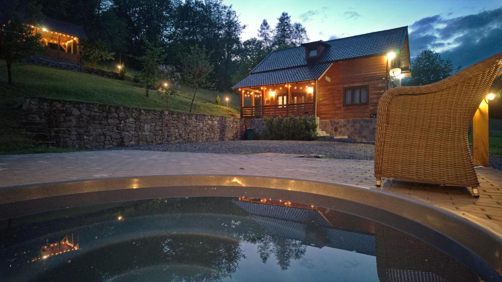 a house with a pool and two chairs and a building at Cabana Codrii Maramuresului in Giuleşti