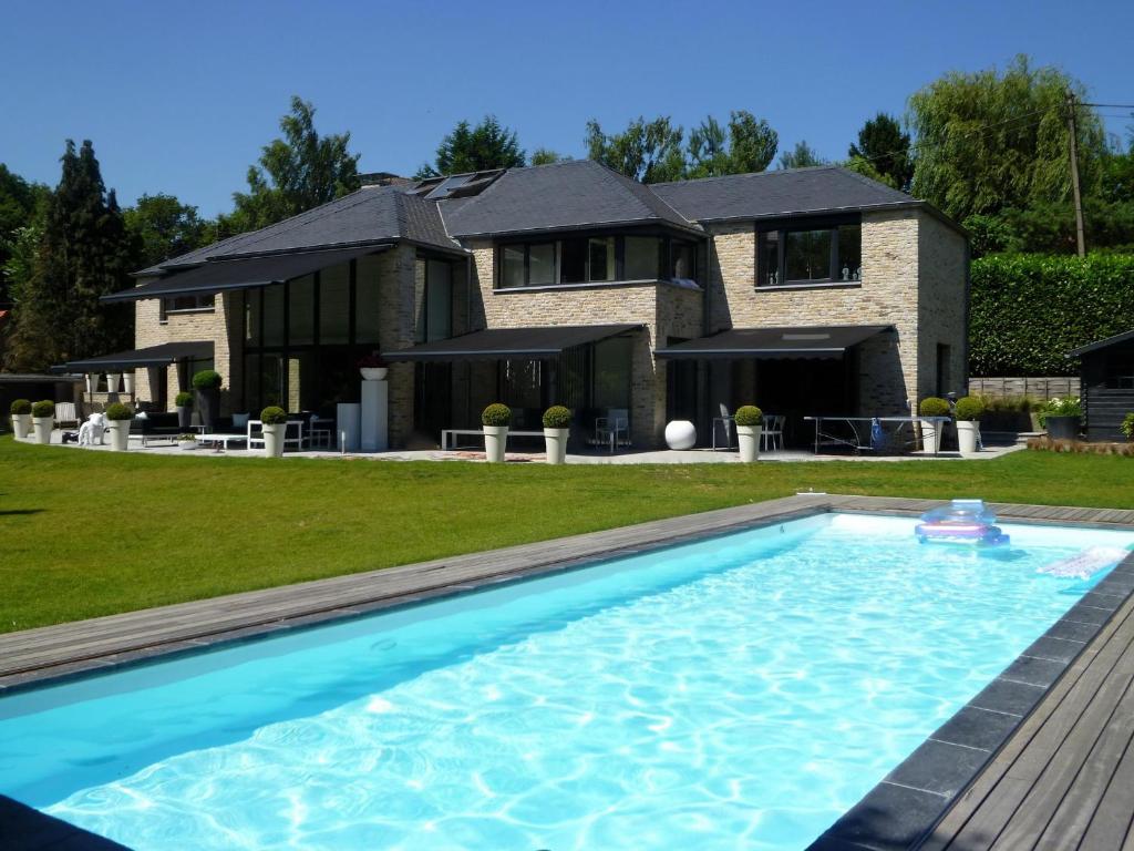 a house with a swimming pool in front of a house at Villa Tiffany in Braine-lʼAlleud