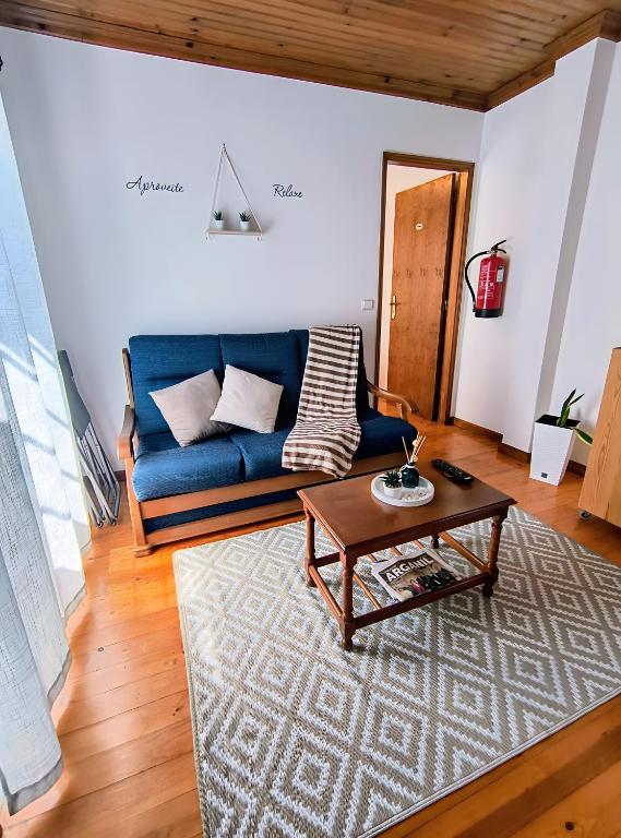 a living room with a blue couch and a coffee table at Refúgio do Xekeraute in Piódão