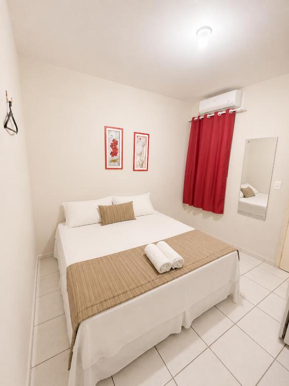 a white bedroom with a large bed with a red curtain at Center 1 Hotel in Fortaleza