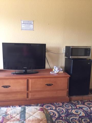 a bedroom with a television on a dresser with a refrigerator at Lake Palestine Motor Inn in Coffee City