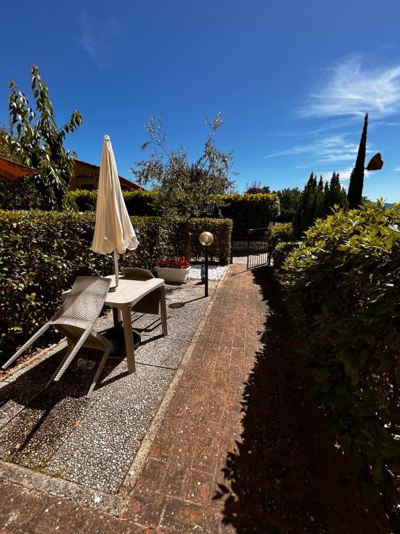 a patio with an umbrella and a chair and a table at La Sosta Nel Chianti in Castelnuovo Berardenga