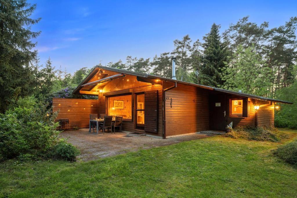 a small wooden cabin with a patio in a yard at Ortheide 68 in Böddenstedt