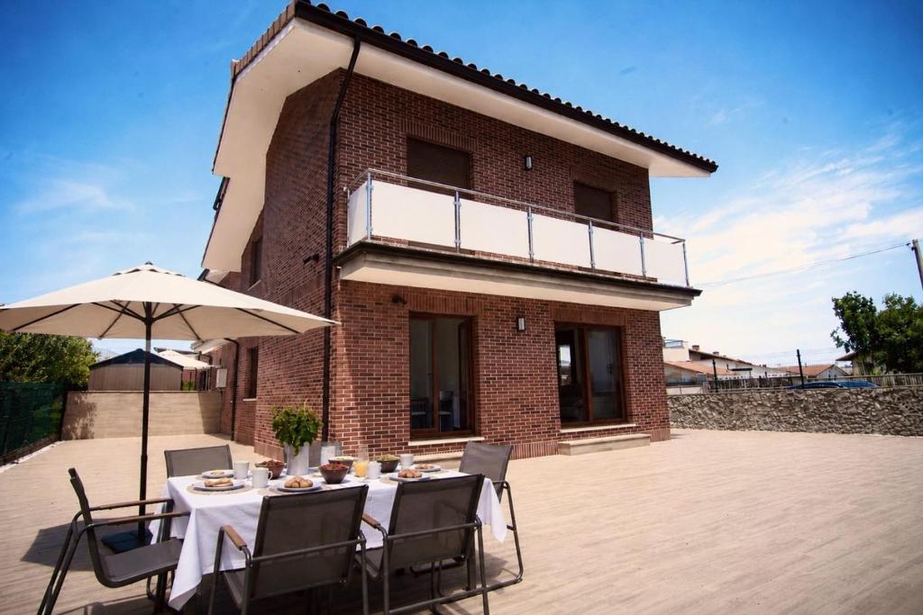 a table with an umbrella in front of a building at La Villa de Miera - 12809 in Ajo
