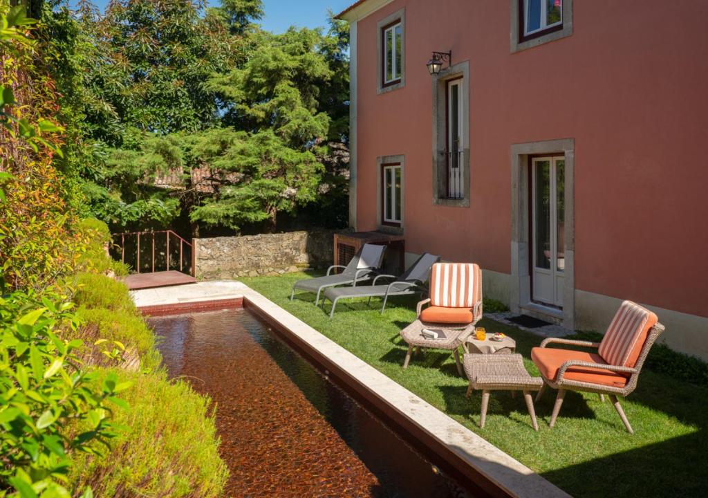 a yard with chairs and a pool in front of a house at Rosegarden Essence Sintra AL - by Unlock Hotels in Sintra