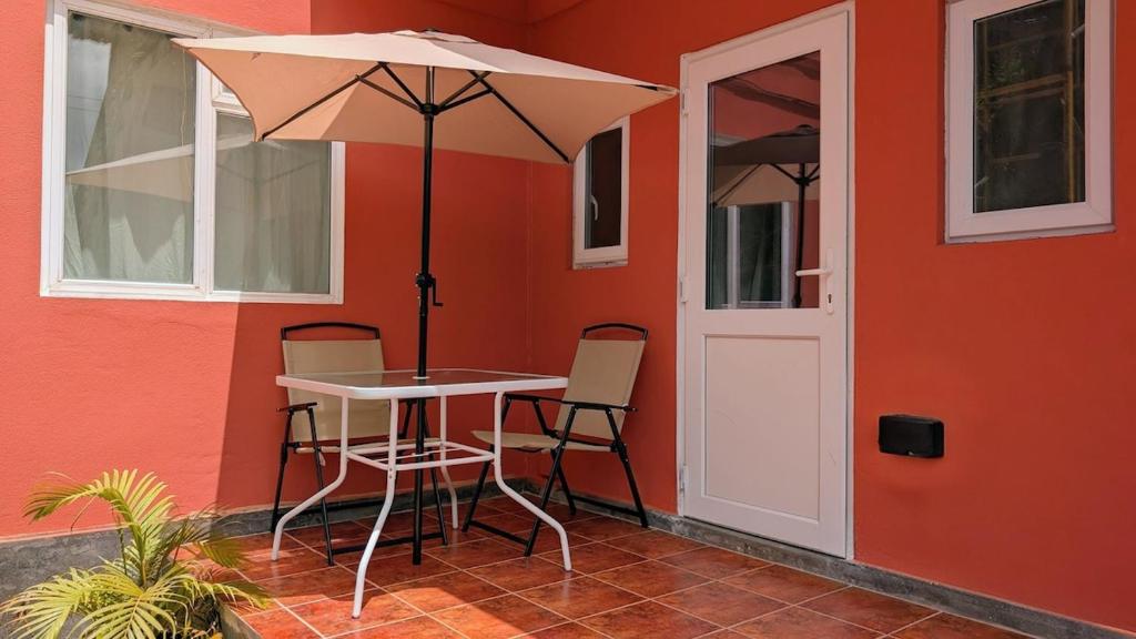 a table with chairs and an umbrella next to a building at Beach Bay Terrace with Mountain views in Buccament
