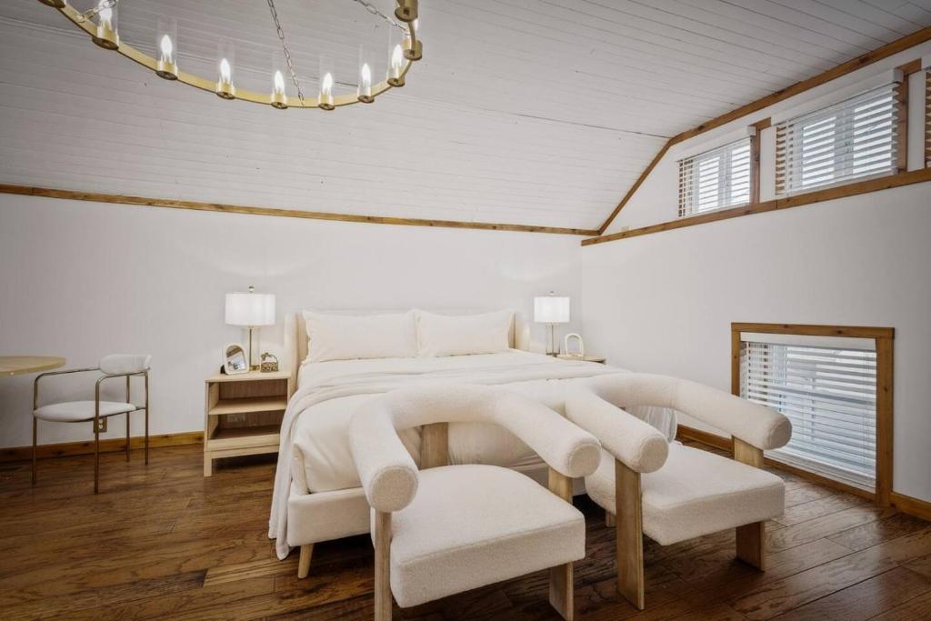 a white bedroom with a large bed and a chair at Chic Retreat on Broadway Street in Grove City