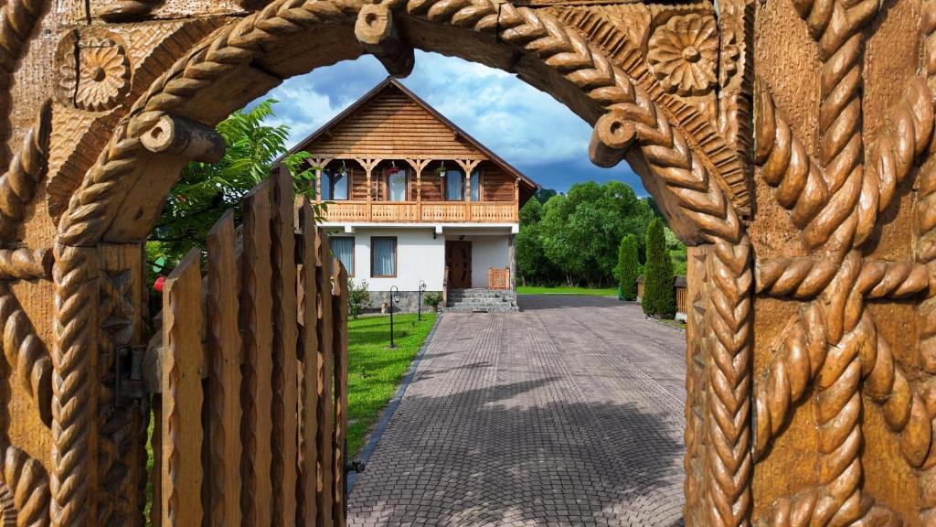a house through an archway in front of a fence at Acasa in Maramures in Fereşti