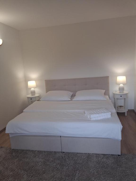 a bedroom with a large white bed with two lamps at Pod jedľou in Liptovský Trnovec