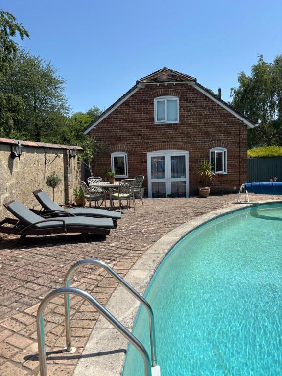 a swimming pool in front of a house at Brook Lodge, One bed house in AONB Dorset with swimming pool in Iwerne Minster