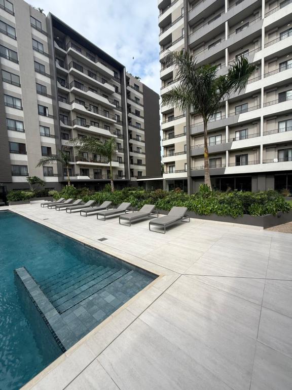 a swimming pool with lounge chairs in front of a building at Summers luxury at Bantree in Accra