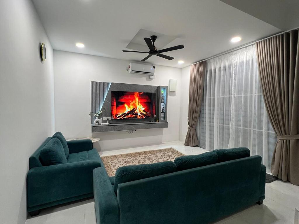 a living room with two green couches and a fireplace at Seroja Homestay Gopeng in Gopeng