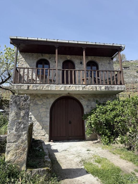 a house with a wooden door and a balcony at uBa Vineyard Stay con vistas al Miño Ribeira Sacra in Chantada