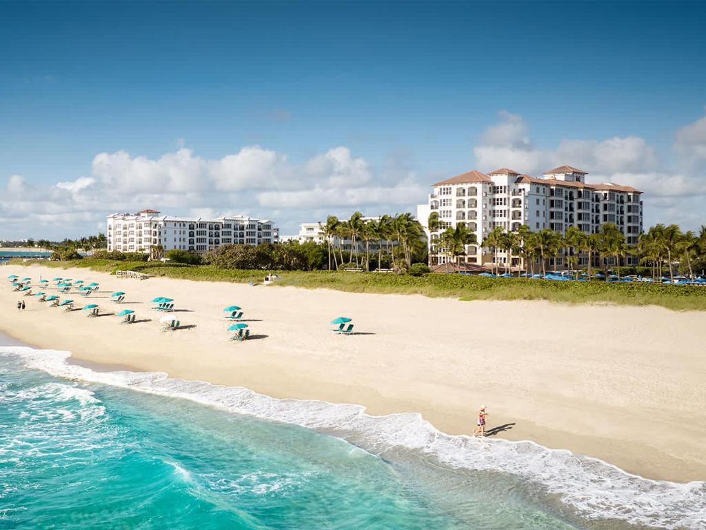 a beach with a bunch of chairs and umbrellas at Ocean Pointe Resort One-Bedroom Villa in Palm Beach Shores