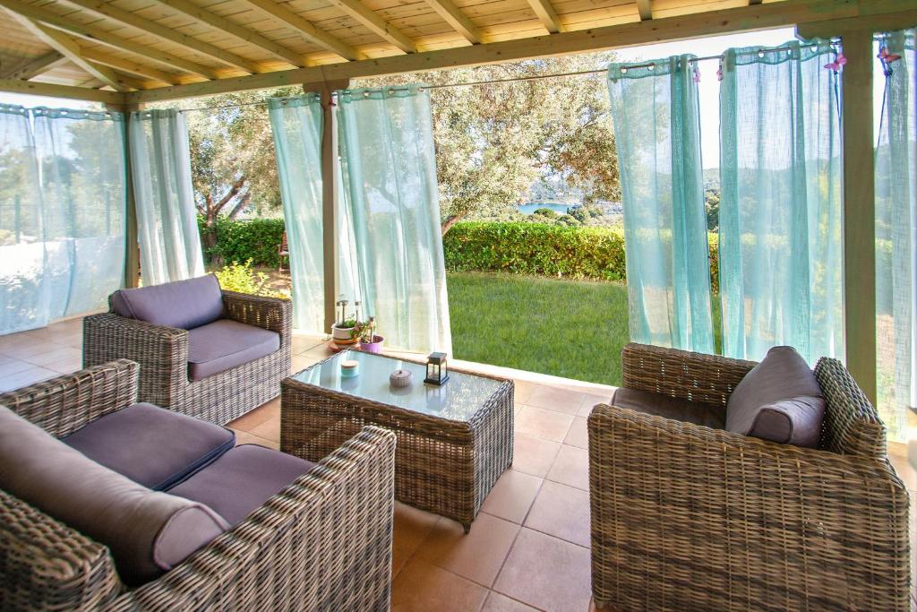 a screened in porch with wicker chairs and a table at Ilios house in Achladies