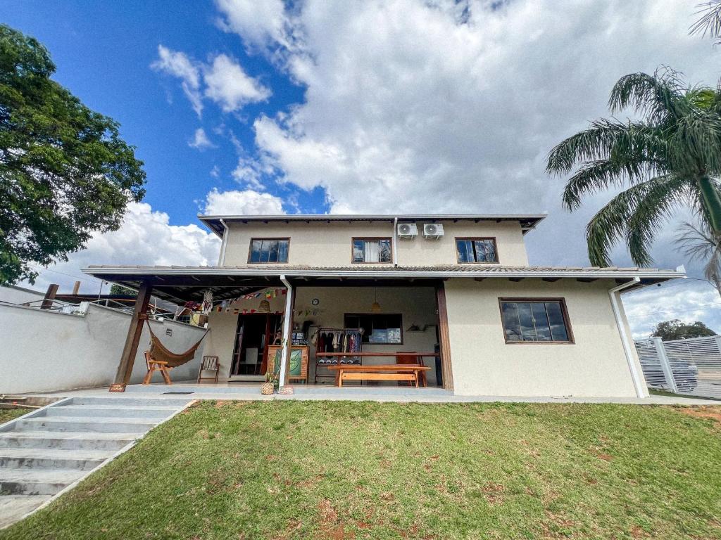 a white house with a porch and a palm tree at Jungla House Hostel in Alto Paraíso de Goiás
