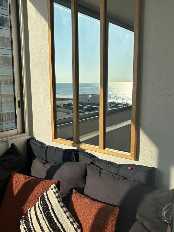 a couch in front of a window with a view of the ocean at Saint Hilaire sea view accommodation in Saint-Hilaire-de-Riez