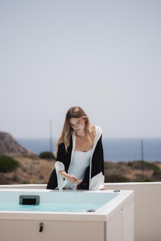 a woman sitting at a table with a glass of wine at Sea Lily Suites Milos in Paleochori