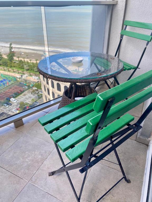 a green chair and a glass table on a balcony at Sea Towers 2 room apartment in Batumi