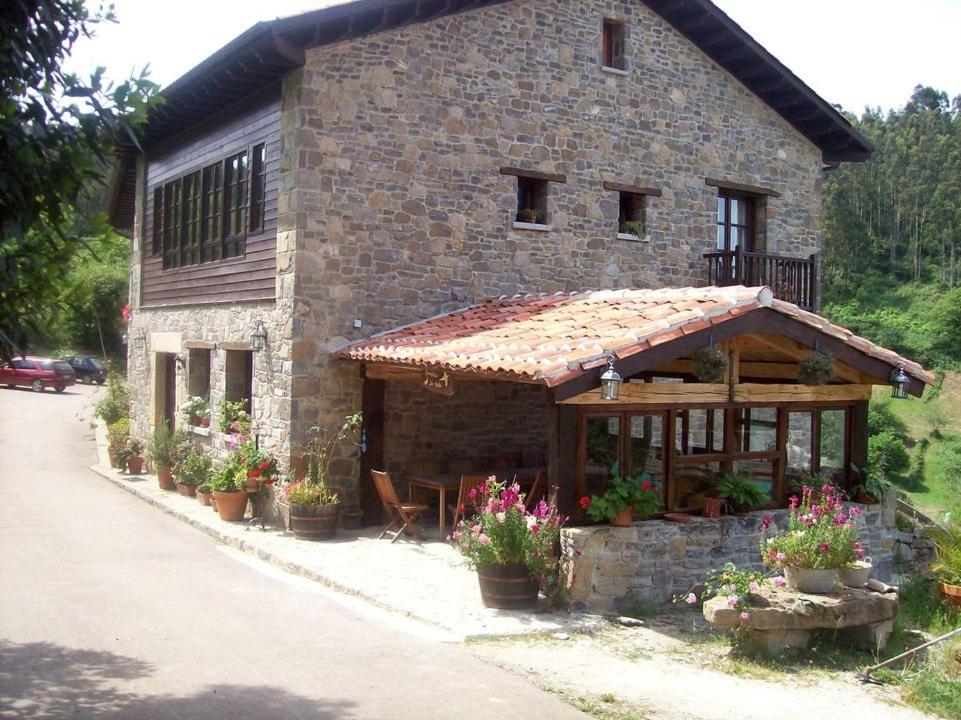 a brick building with a porch with flowers on it at Casa de Aldea Los Valles in La Llera