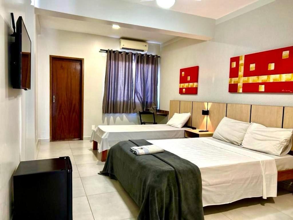 a hotel room with two beds and a television at Hotel JCA Uberlândia in Uberlândia