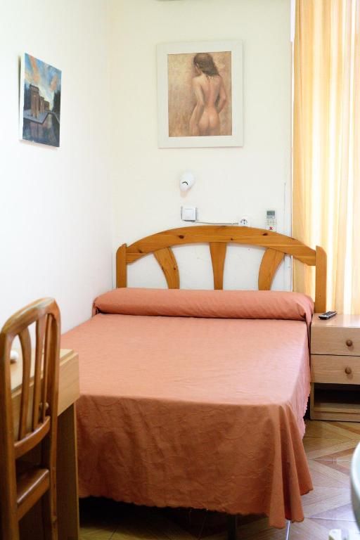 a bedroom with a bed with a orange bedspread at Hostal Fuentesol in Madrid