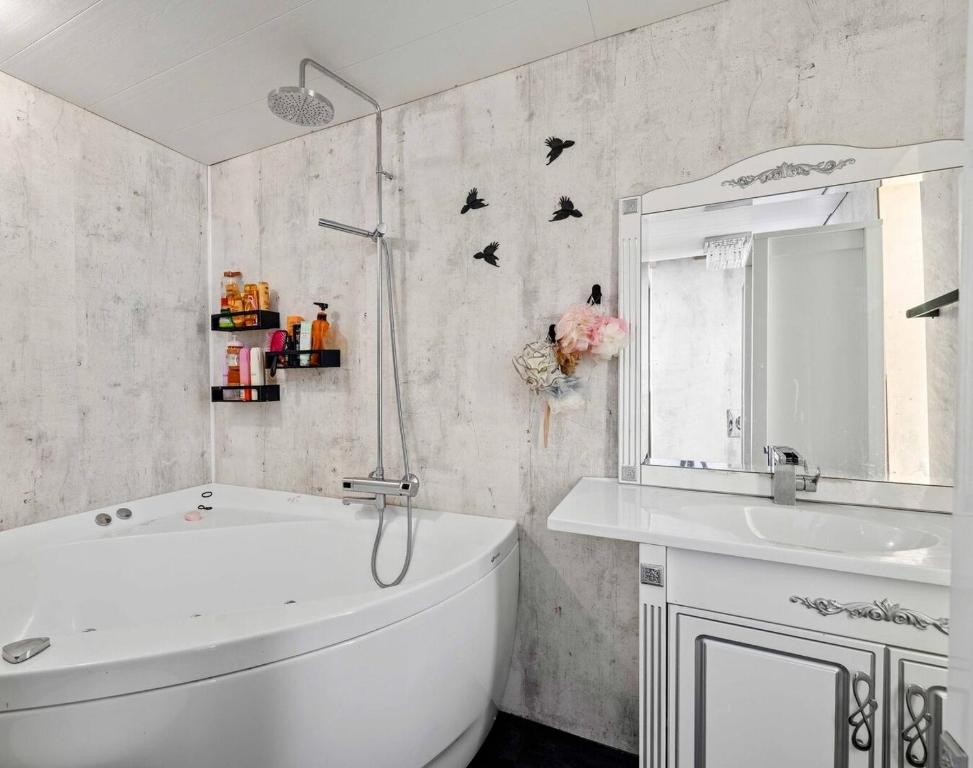 a white bathroom with a tub and a sink at Tjarnarkot in Sandgerði