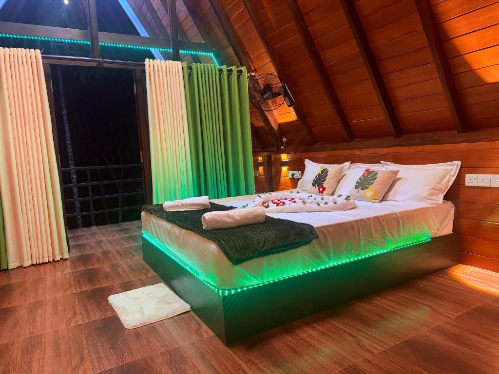 a bedroom with a large bed with green lighting at Rainforest Emerald Haven in Deniyaya