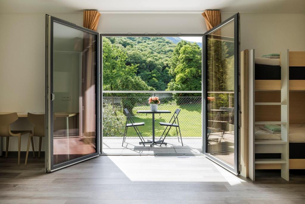 a glass door leading to a balcony with a table and chairs at Ostello Sport Center in Monte Ceneri