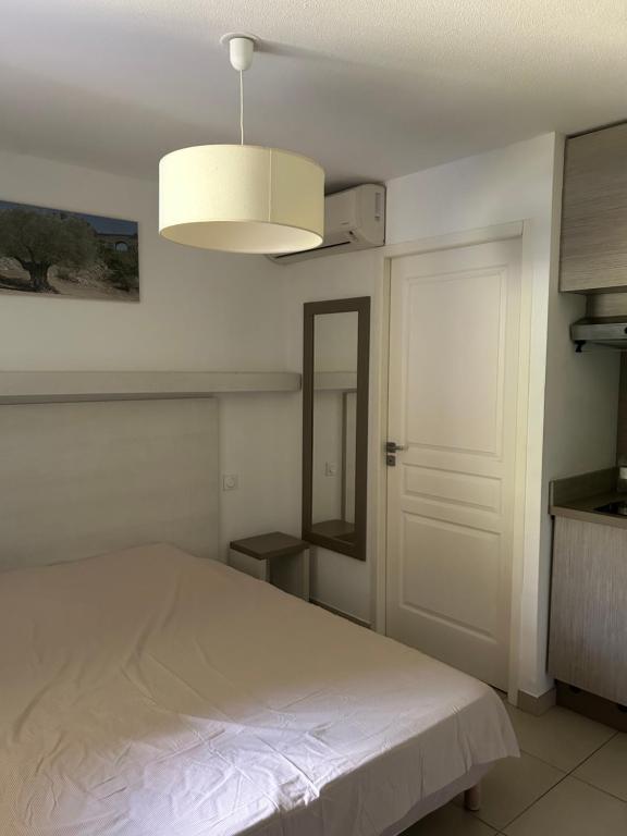 a bedroom with a white bed and a light at Le petit studio du Gard in Remoulins