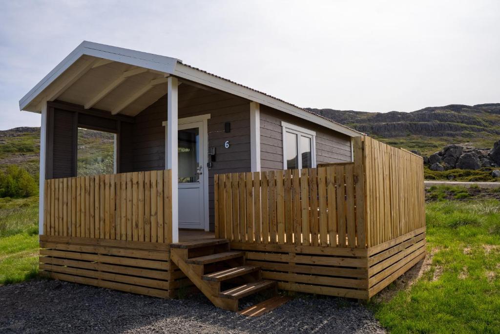 a small cabin with a porch and a door at Hvammur 6 with private hot tub in Hafnarhólmur
