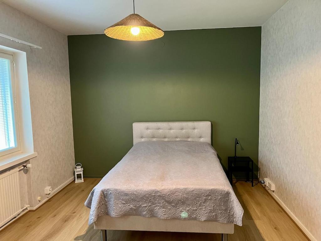 a bedroom with a bed in a green wall at Spacious one room apartment in Vaasa