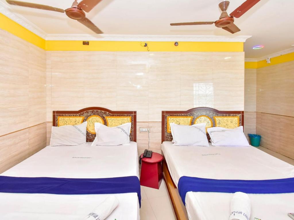 two beds in a room with yellow walls at SNN Residency in Rāmeswaram