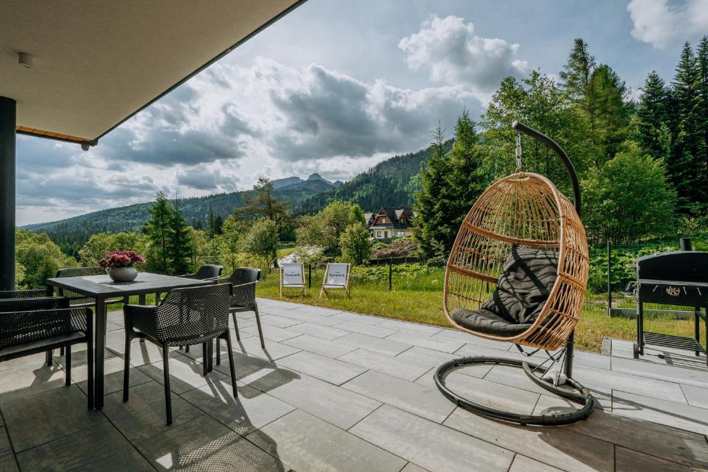 a rattan chair sitting on a patio with a table at Domki Tymianek & Melisa in Kościelisko