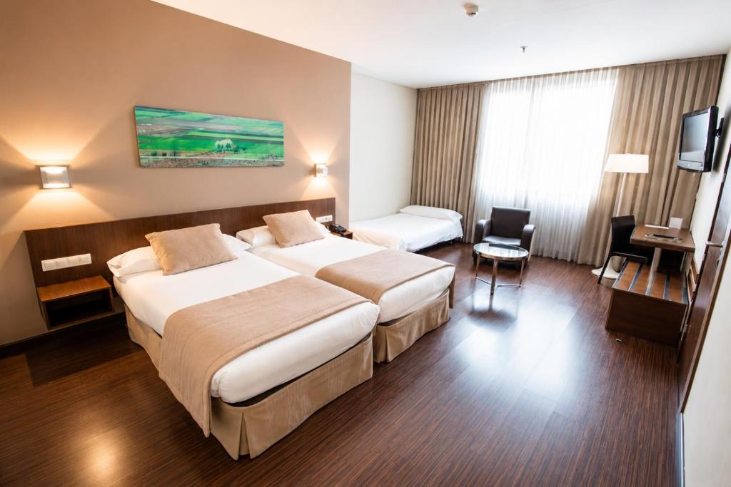 a hotel room with two beds and a desk at ARVA Abad San Antonio in León