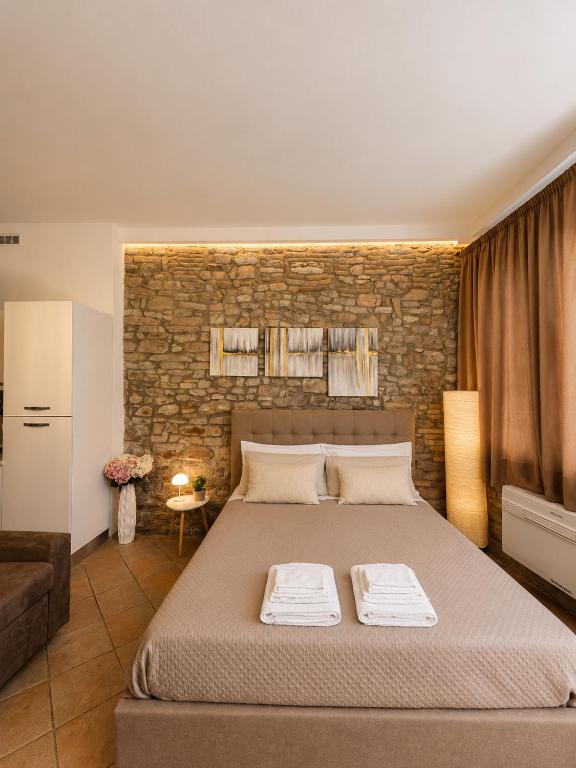 a bedroom with a large bed and a brick wall at Giulivi Assisi Apartments in Assisi