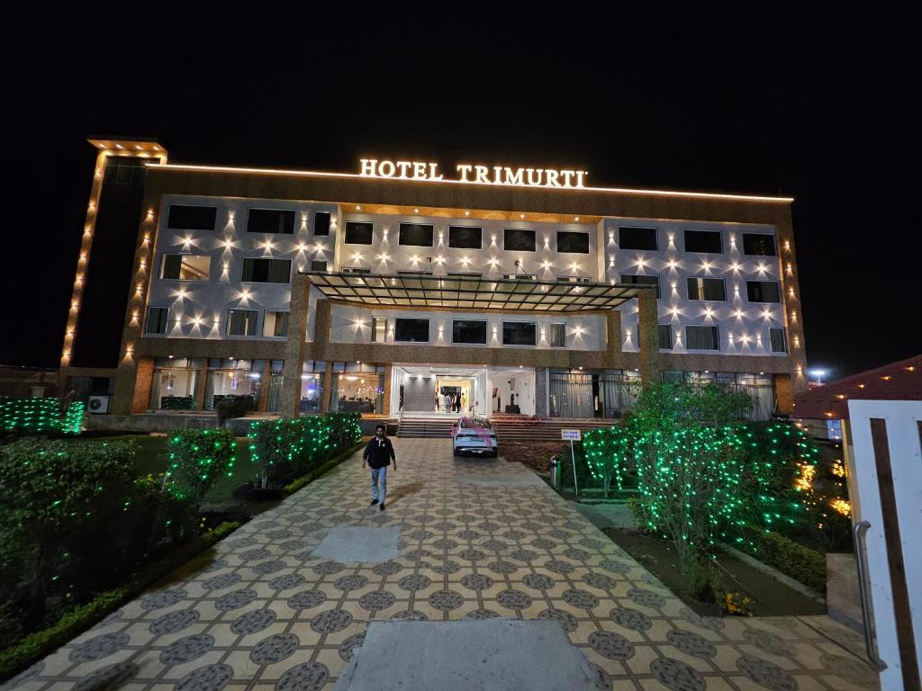 a man walking in front of a hotel at night at Hotel Trimurti By Carlton Suites in Ayodhya