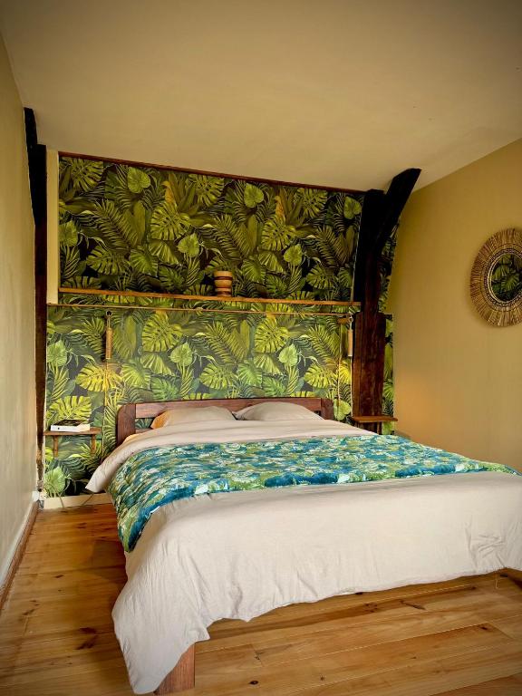 a bedroom with a large bed with a green headboard at La Pépite in Sénac