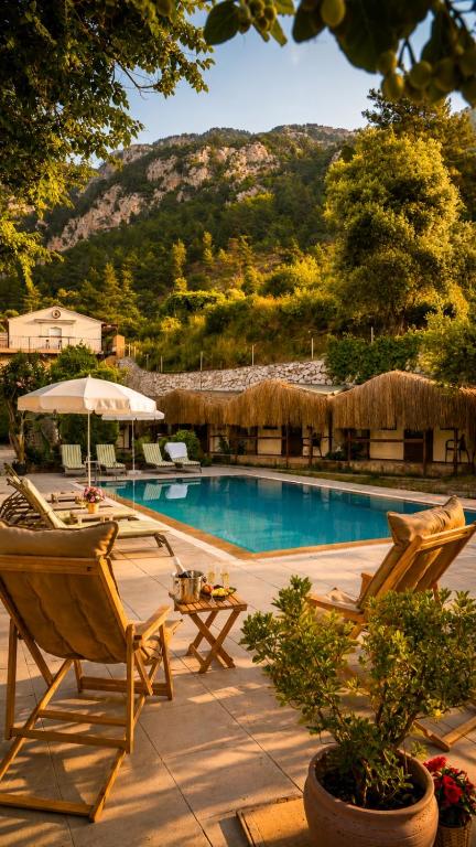 a swimming pool with two chairs and an umbrella at La Dia Hotel Faralya in Fethiye