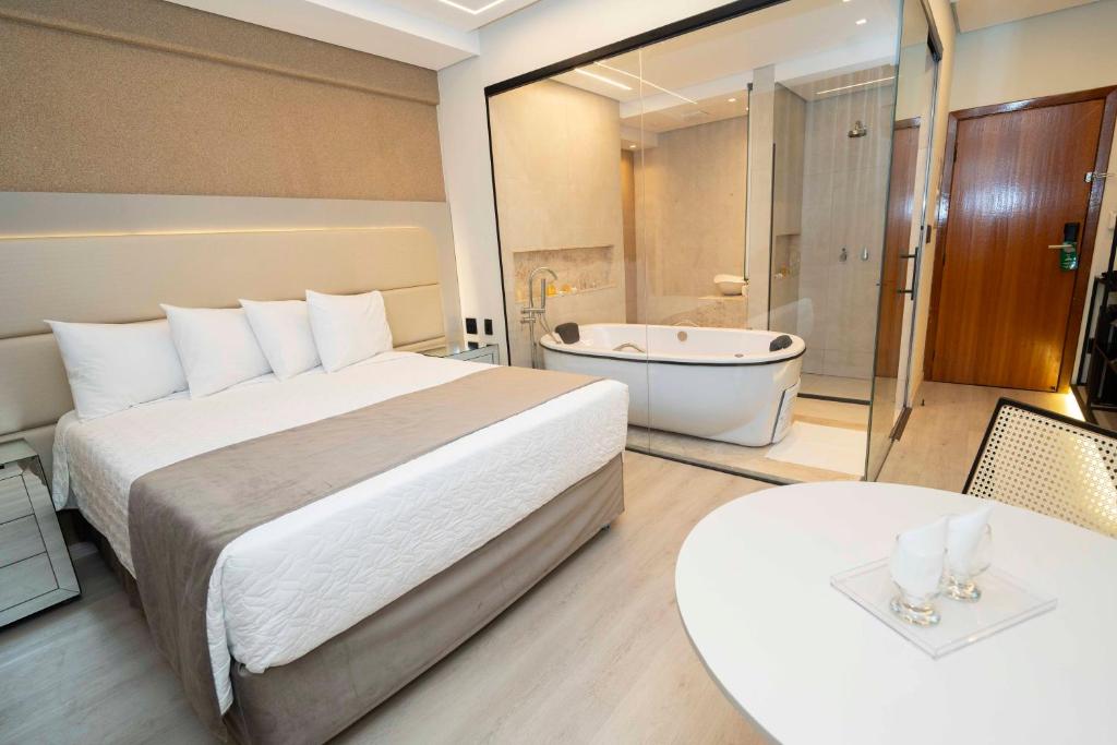 a hotel room with a bed and a bath tub at Hotel Capital Das Pedras in Teófilo Otoni