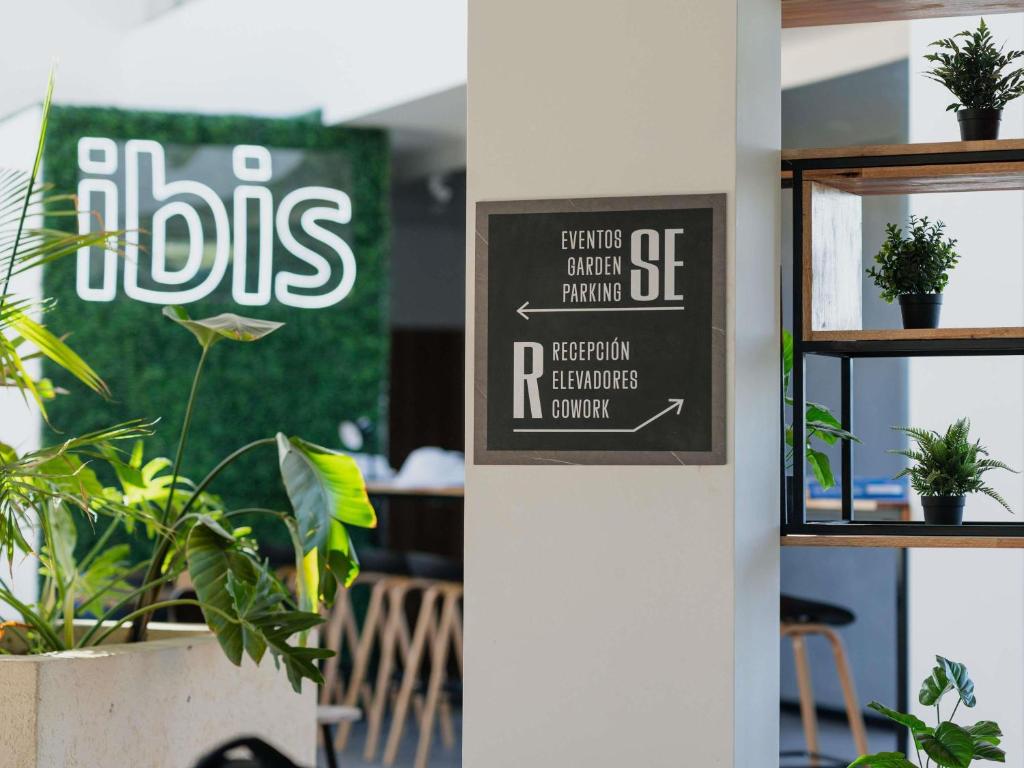 a sign in an office with plants on a shelf at Ibis Puerto General San Martin in San Lorenzo