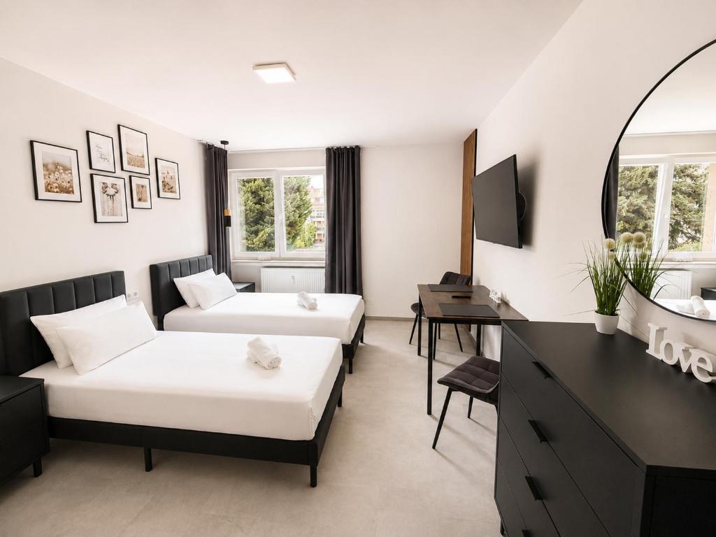 a hotel room with two beds and a desk at Lipp Apartments in Cologne