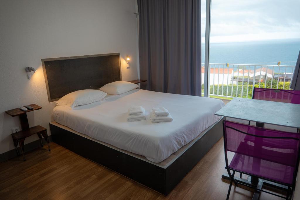 a bedroom with a bed with a view of the ocean at GarçaView in Vila Franca do Campo