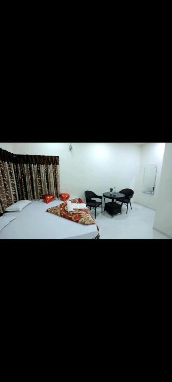 a bedroom with a bed and two chairs and a table at krishna suraj villa in Chikalda