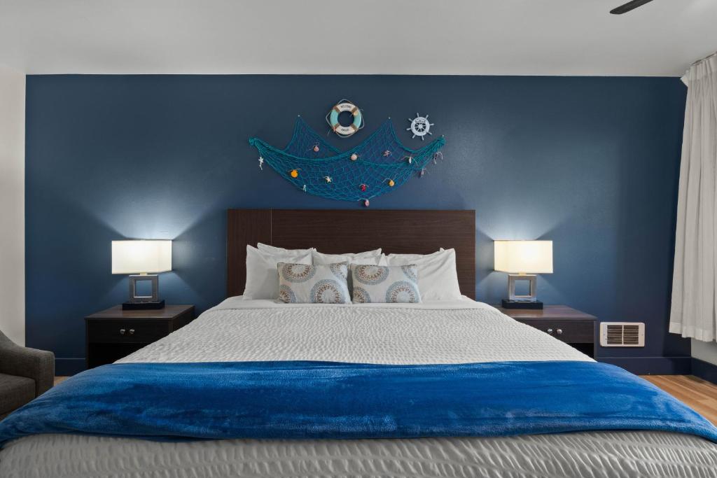 a blue bedroom with a large bed with two lamps at Sunset Haven Oceanfront Hotel in Depoe Bay